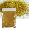A clear plastic bag filled with holographic gold glitter powder next to a loose pile of the same glitter.