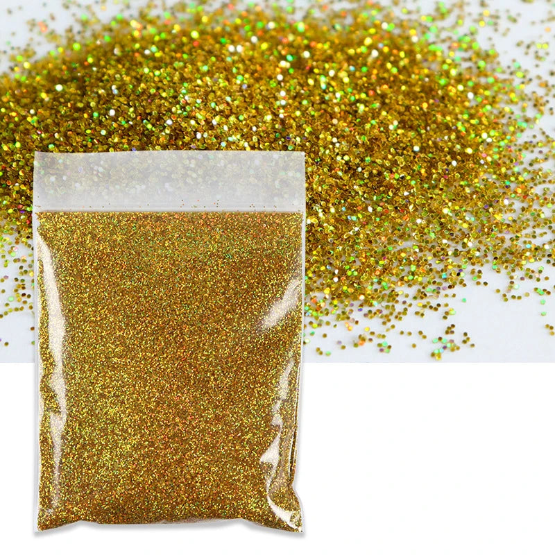 A clear plastic bag filled with holographic gold glitter powder next to a loose pile of the same glitter.