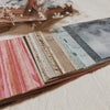 A close-up view of a pack of rainbow textured paper for junk journals and collage art.