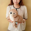 A woman holds a brown seal plush toy against her white shirt.