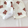 Light beige casual pants featuring a repeating brown bear print on the fabric.