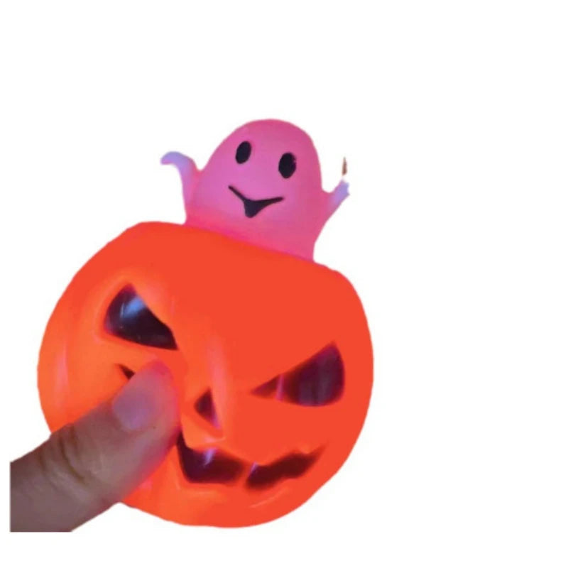 An orange Halloween pumpkin squishy fidget toy with a pink ghost face on top being held by a hand.
