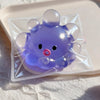 A purple squishy bubble squid stress relief toy packaged in clear plastic on a white surface.