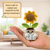 A hand holds a handmade crochet sunflower pot doll with a message about making a difference.