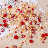 A scattered mix of clear, amber, pink, and red resin rhinestones and pearls for craft and nail art.