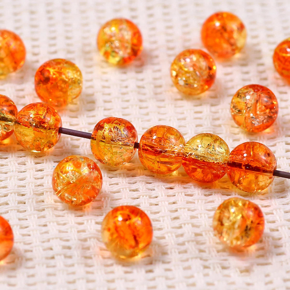 Golden gradient crystal glass beads with a crackle finish scattered on a white surface