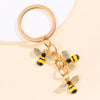 Gold-toned keychain featuring enamel bees and flowers on a circular ring.