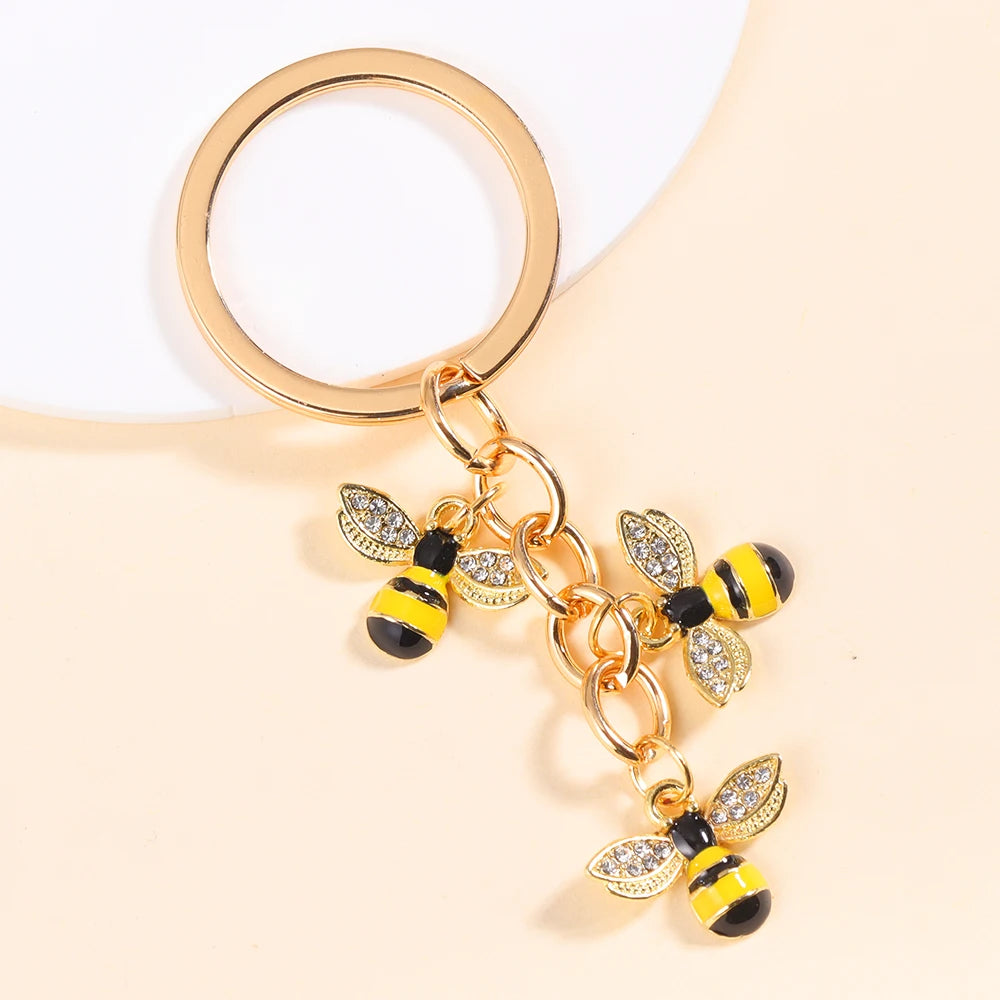 Gold-toned keychain featuring enamel bees and flowers on a circular ring.
