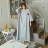 A woman models a long, gray and white striped short-sleeve lounge dress in a modern interior setting.