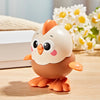 A small, round orange and white wind-up chick toy with a pull chain sitting on a wooden surface next to white boxes and yello