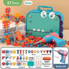 A green dinosaur-themed building toy set featuring various screws, nuts, and a pink electric drill.