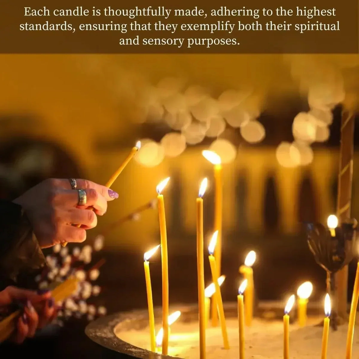 A hand holds a lit natural beeswax taper candle in a warm, dimly lit setting.