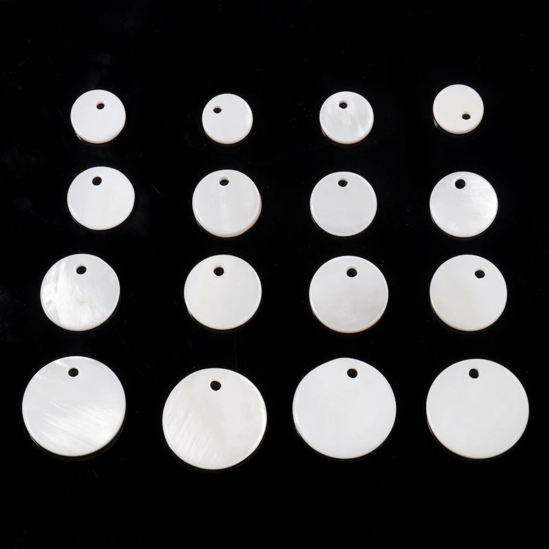 A row of twelve natural white shell beads in various round sizes arranged on a black surface.