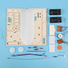 A wooden paddle boat kit featuring a wooden board, foam paddle, and various electronic components for a science project.