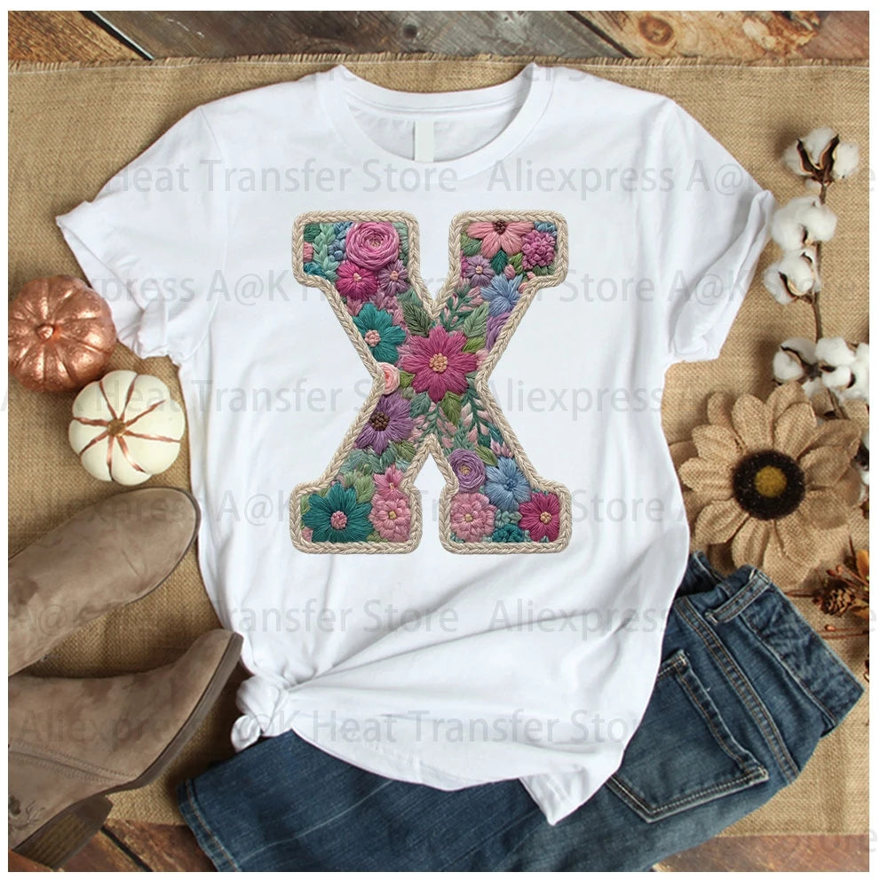 White t-shirt featuring a large embroidered floral letter X design on the chest