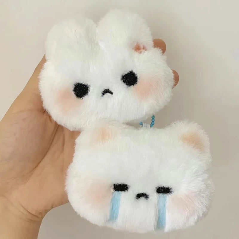 A white fluffy rabbit plush toy with sad eyes and blue tear marks is held in a hand.