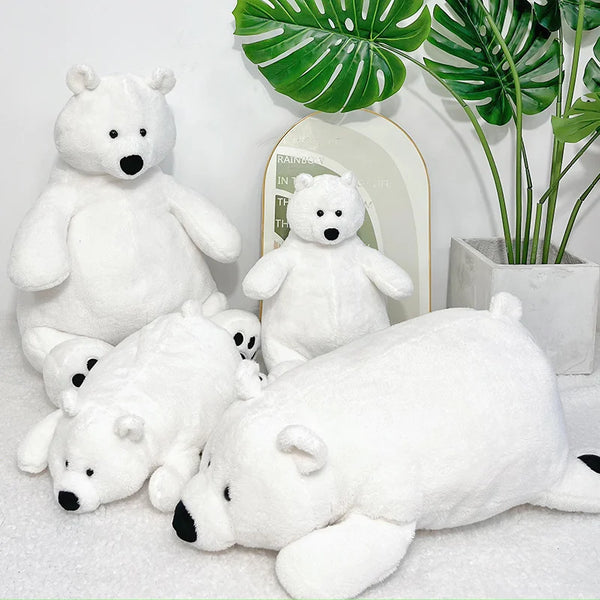Three white plush polar bear stuffed animals sitting in front of a green tropical leaf plant