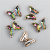 Several iridescent crystal butterfly charm beads are displayed against a gray background.