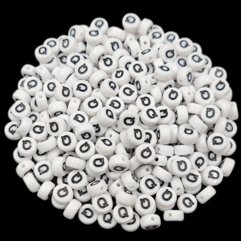 A pile of small white acrylic alphabet letter beads for jewelry making