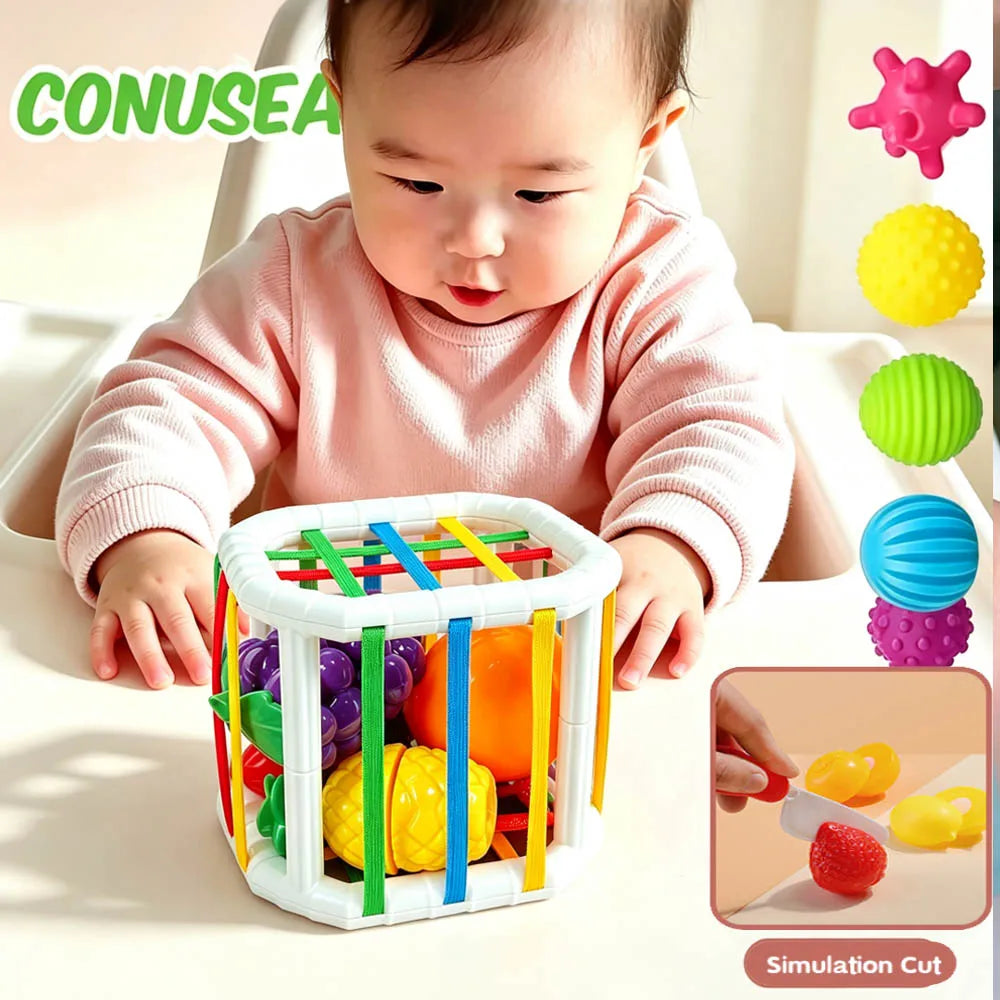 A baby is interacting with a white plastic toy box filled with colorful, round, and shaped objects for sorting and play.
