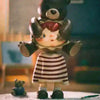 A small brown bear figure with pink hair wearing a striped dress is shown on a white surface.