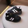 A pair of black and white Adidas-style casual sneakers resting on a white surface.