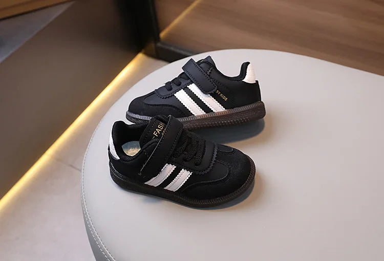 A pair of black and white Adidas-style casual sneakers resting on a white surface.