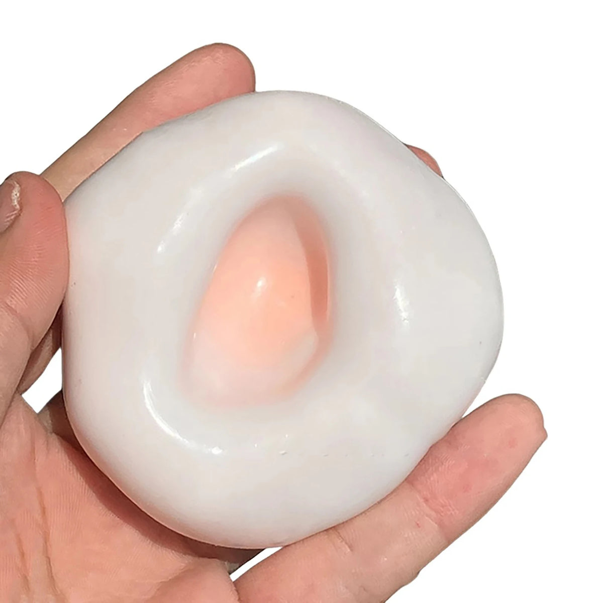 A hand holds a white, squishy sand stress ball with a pink center, used as a sensory fidget toy.