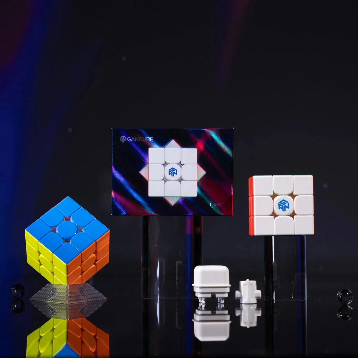 A magnetic speed cube is displayed next to a colorful cube and small white components on a dark surface.