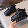 A hand holds a black quilted toddler winter snow boot with a soft sole and Velcro closure.