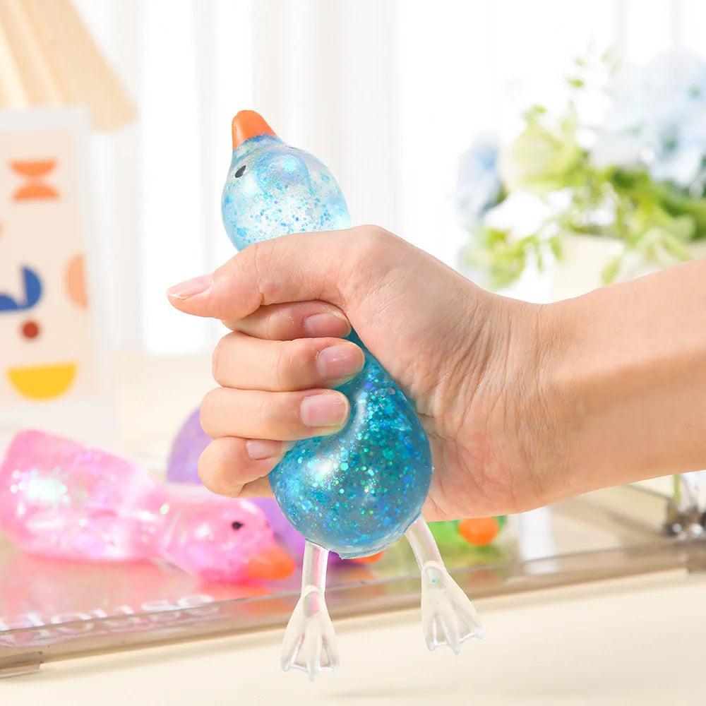 A hand is squeezing a bright blue glittery duck squeeze toy for stress relief.