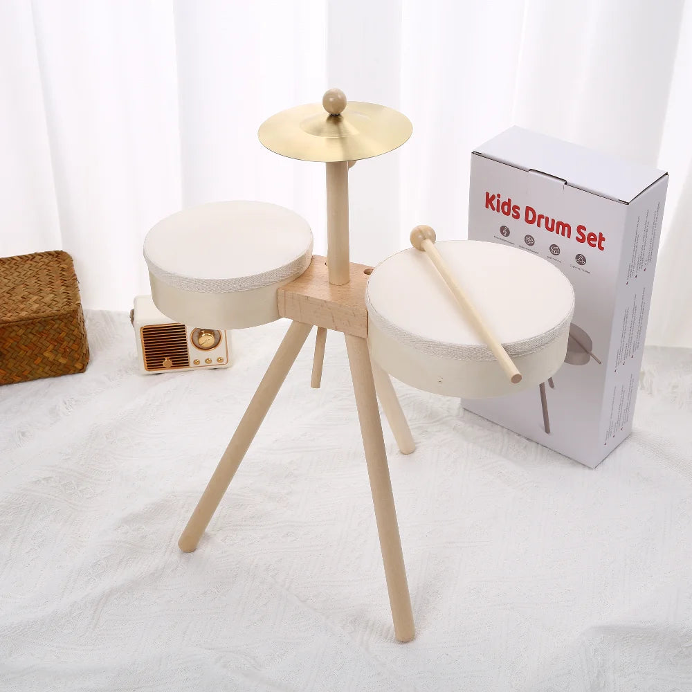 A wooden kids drum set with a light wood stand and two round white drums is displayed on a white surface.