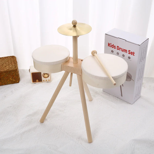 A wooden kids drum set with a light wood stand and two round white drums is displayed on a white surface.