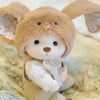 A light brown plush teddy bear with floppy ears wearing a white dress.