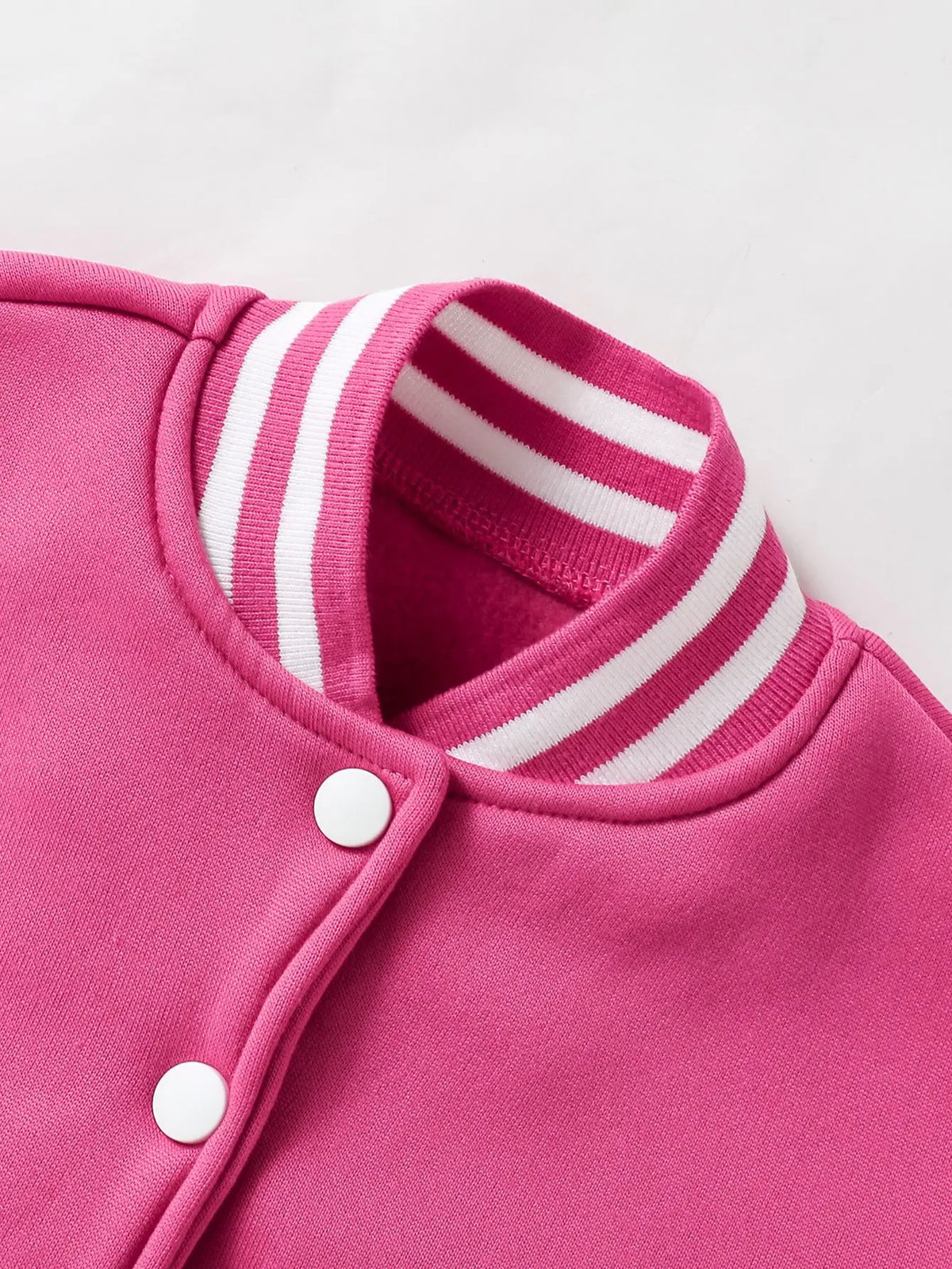 Pink knitted cardigan with white stripes on the collar and a single button closure.