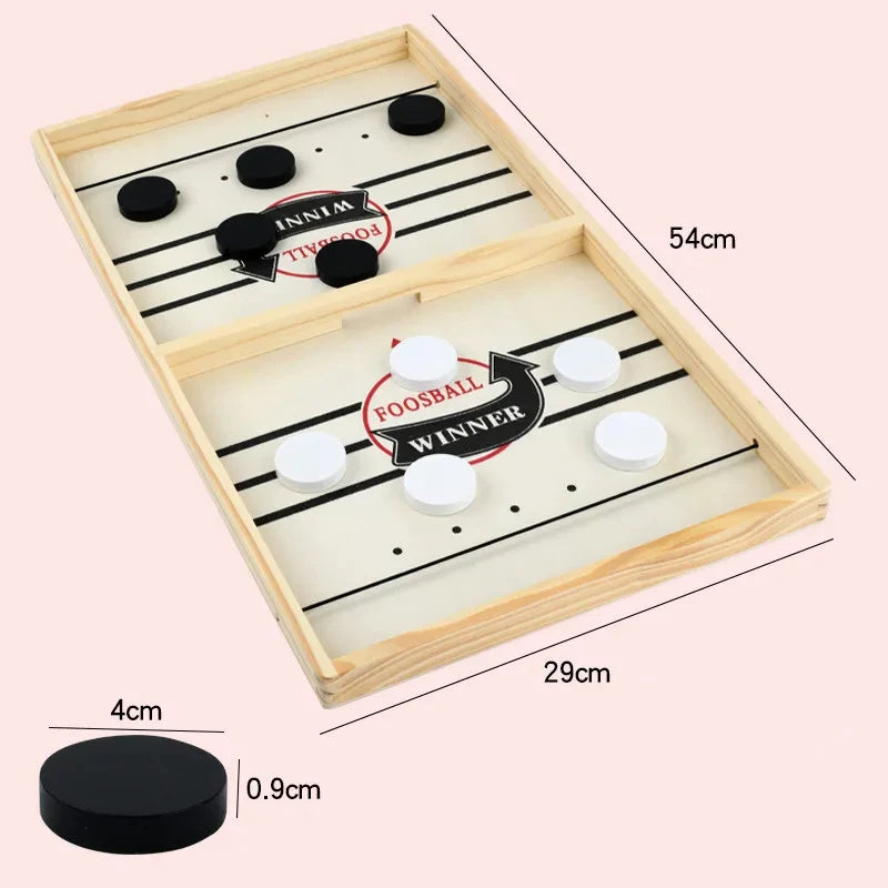A wooden catapult tabletop hockey game board with black and white pucks and a winner marker.