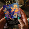 A hand holds an Akashic Oracle Card featuring a silhouette of a figure against an orange and yellow sunset background.