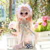 A 17cm articulated princess doll with pink hair and a white floral dress sitting outdoors.