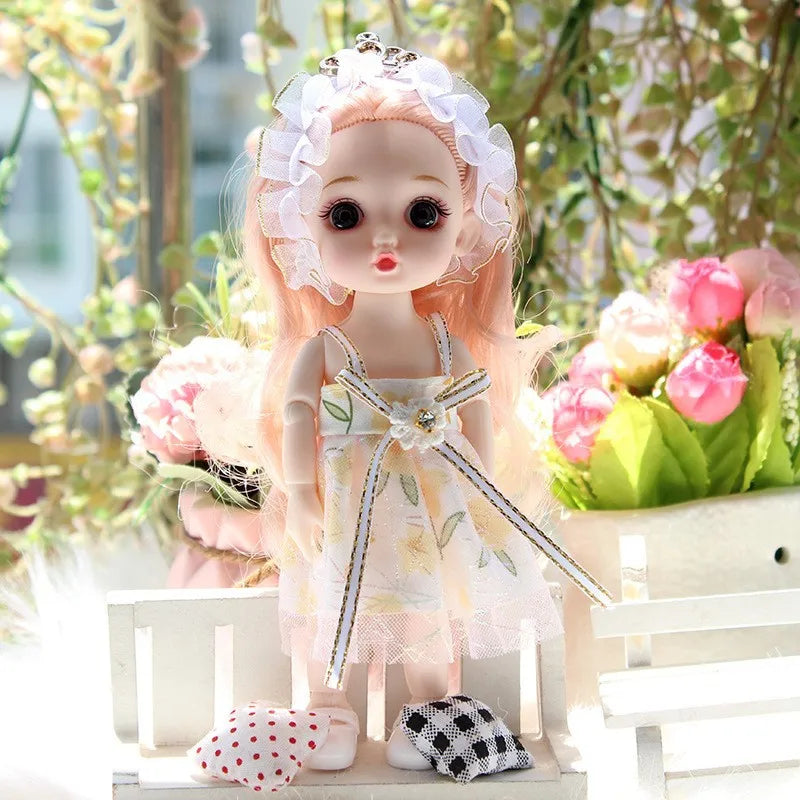 A 17cm articulated princess doll with pink hair and a white floral dress sitting outdoors.