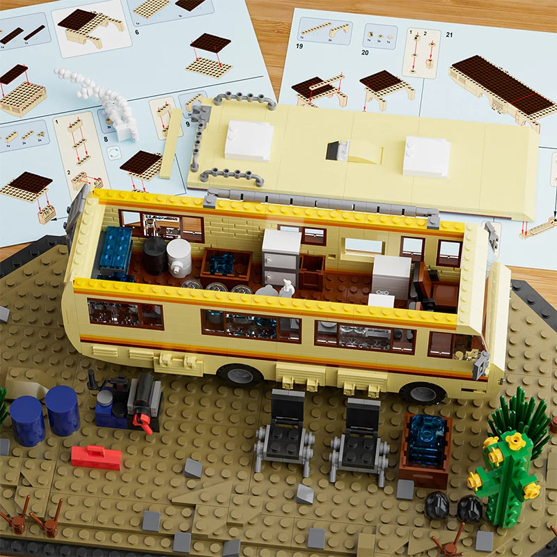 A building block set depicting a yellow RV camper bus with various accessories and a separate structure on a tan baseplate.