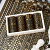 A set of 20 rolls of black and gold foil washi tape displayed in a white box on a patterned surface.
