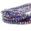 A close-up of dark purple and blue faceted crystal beads used for jewelry making.
