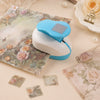 A light blue and white decorative square stamp edge paper is shown next to a white and blue stamp tool on a beige surface.