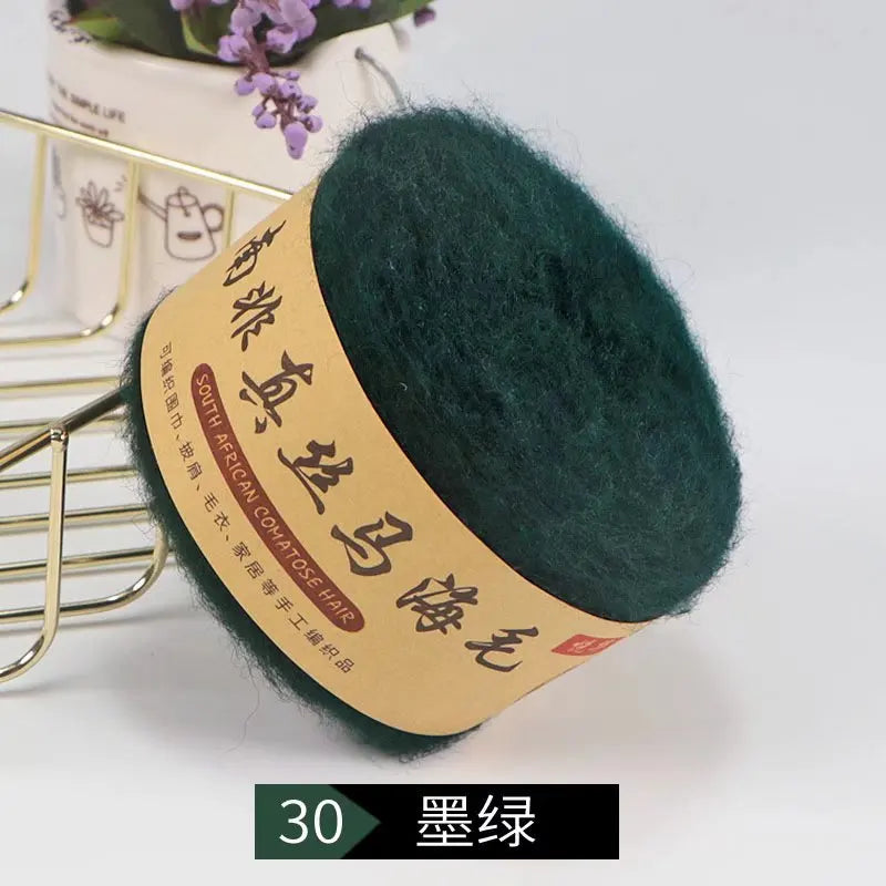 A ball of dark green mohair blended yarn labeled South African mohair for knitting products.