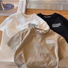 A stack of three kids car print crew neck t-shirts in white, black, and beige.