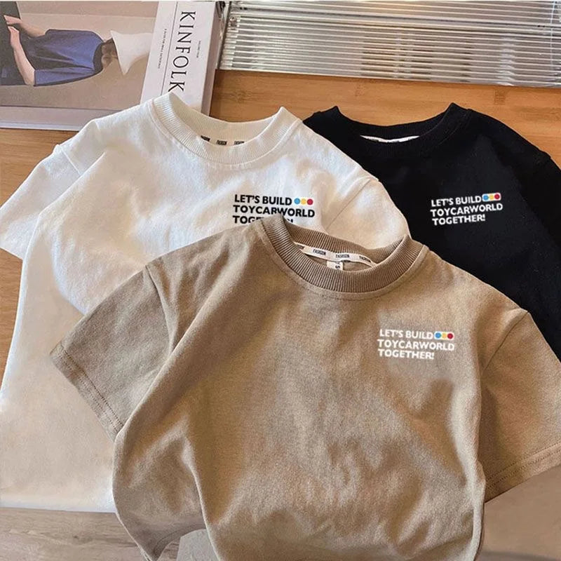 A stack of three kids car print crew neck t-shirts in white, black, and beige.