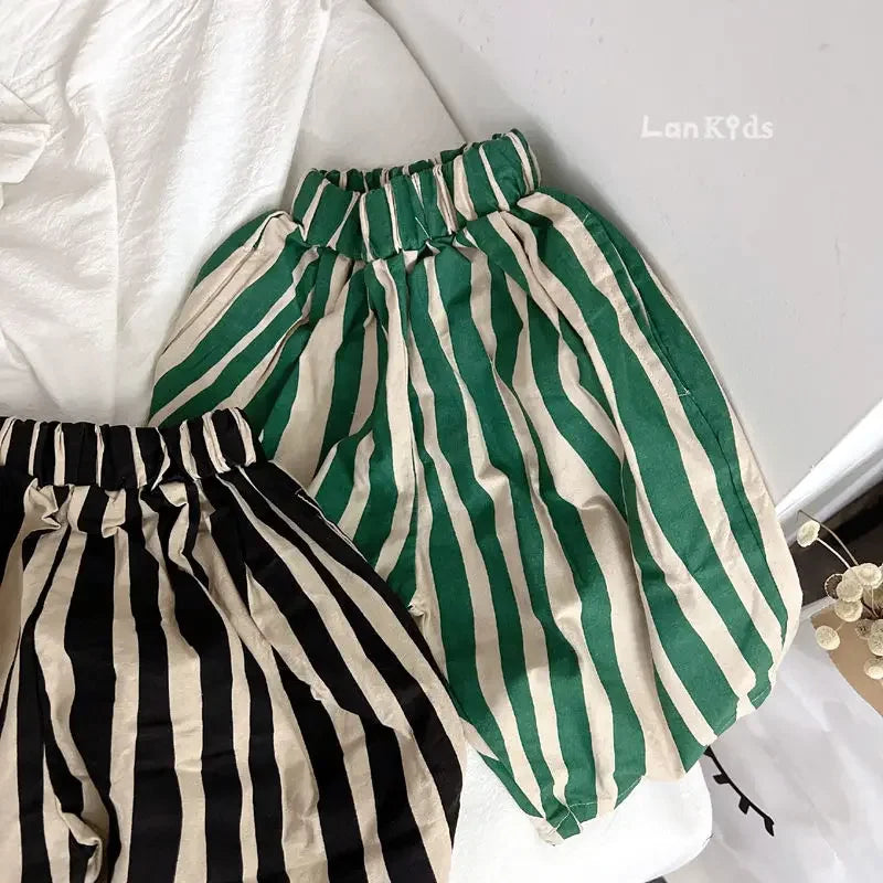 Green and cream striped cotton harem pants for kids laid out on a white surface.