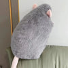 A realistic plush rat stuffed animal doll with gray fur and pink ears is displayed on a light green surface.