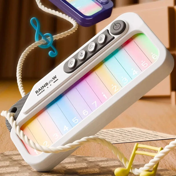 A white rainbow piano keyboard musical toy is shown with a string and yellow keys on a wooden surface.