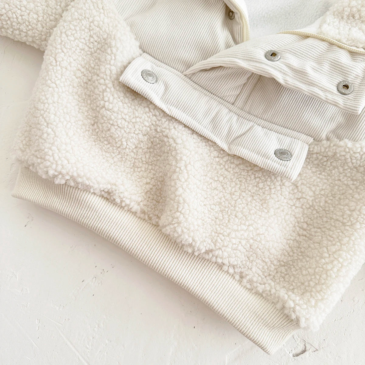 A cream colored toddler fleece-lined winter coat with a half-zip collar shown flat lay.